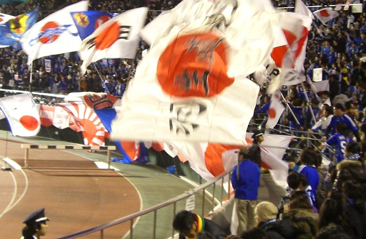 A packed stand of Japan supporters waving Hinomaru flags
